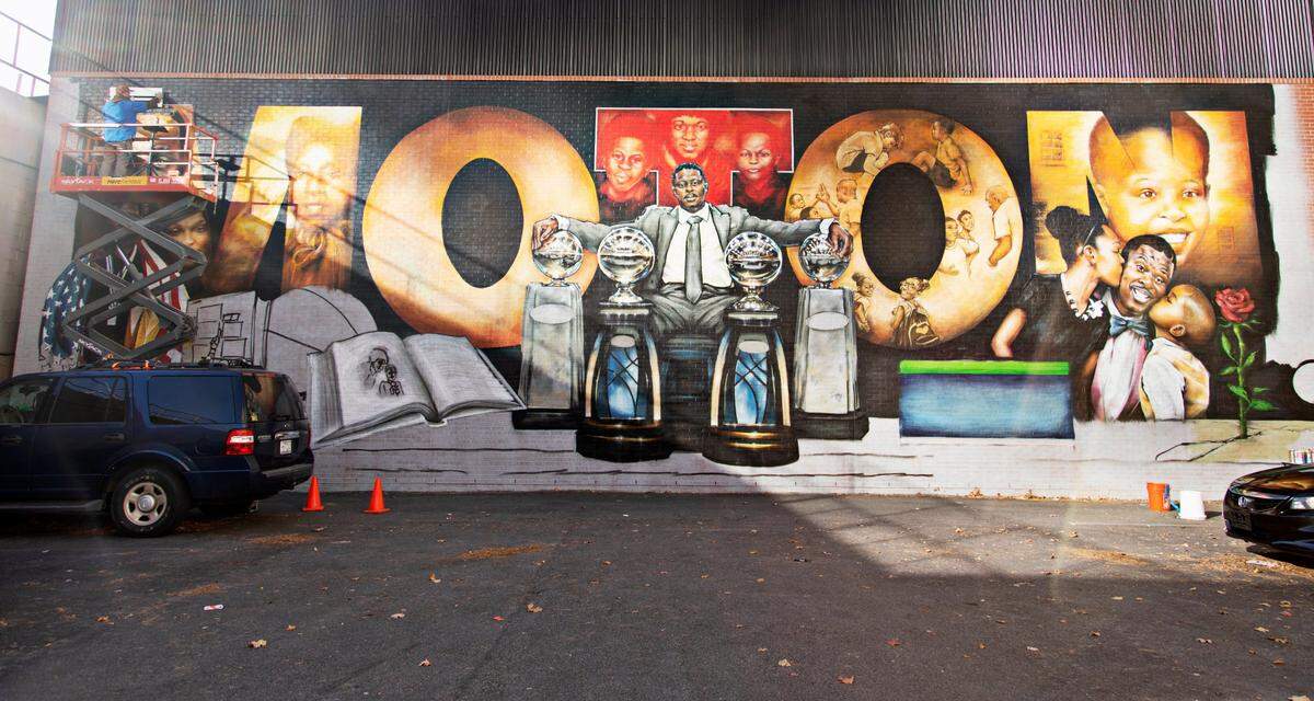 Artist Sean Kernick works on the finishing touches (upper left) of his mural to honor NCCU coach LaVelle Moton on Salibury St. in downtown Raleigh on Tuesday, Nov. 23. 2021.