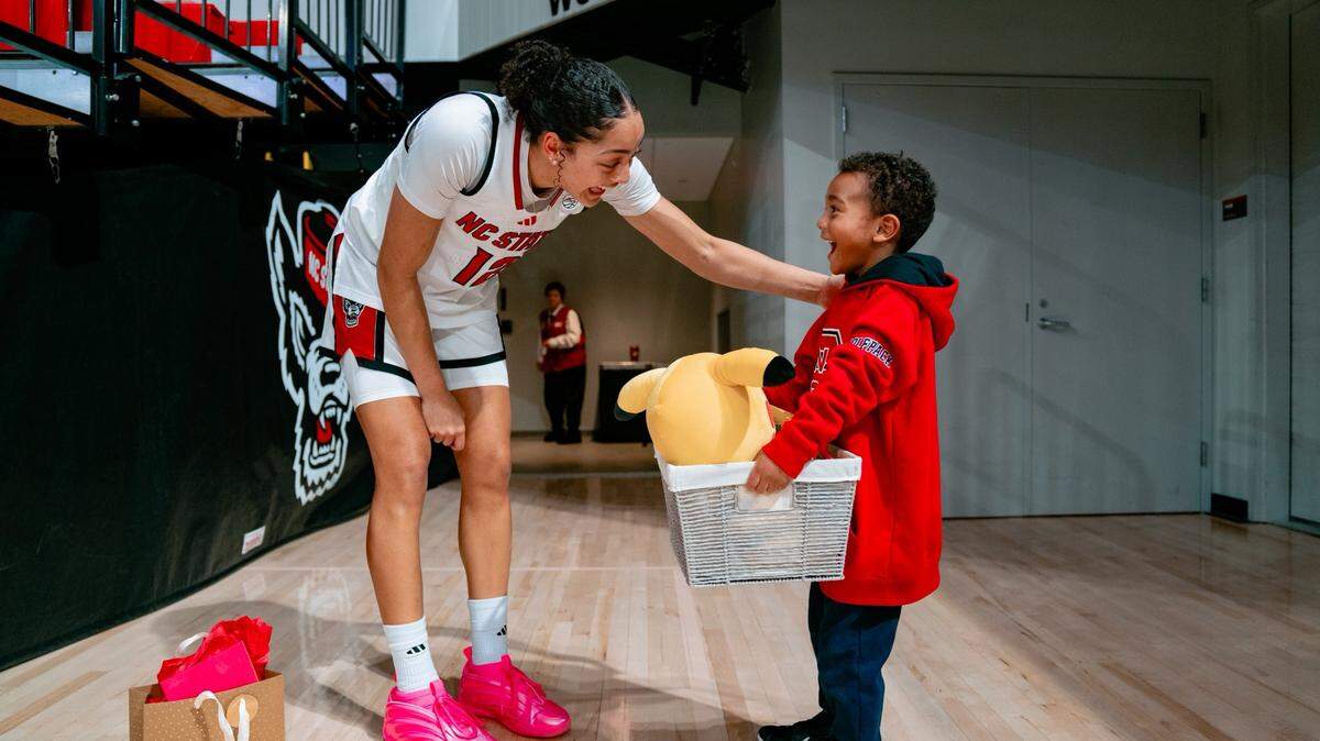 N.C. State forward Khamil Pierre exchanges gifts with fan Braylon Collins after a game at Reynolds Coliseum in Raleigh, North Carolina.