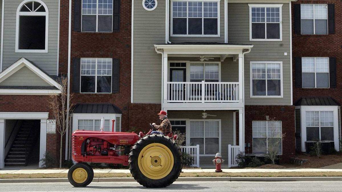 Grover Lewter drives his red Massey-Harris "44 Special" tractor past new apartments at Carpenter Village on Morrisville-Carpenter Road in 2003.