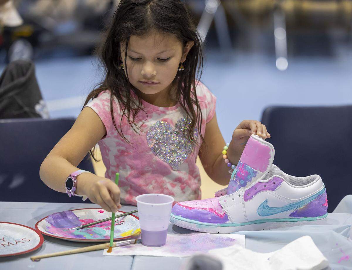 Gisele Lyon of Apex, N.C paints a pair of shoes, during the Shoes 4 Hope event on Sunday, December 14, 2025 at the Smith Center in Chapel Hill, N.C.