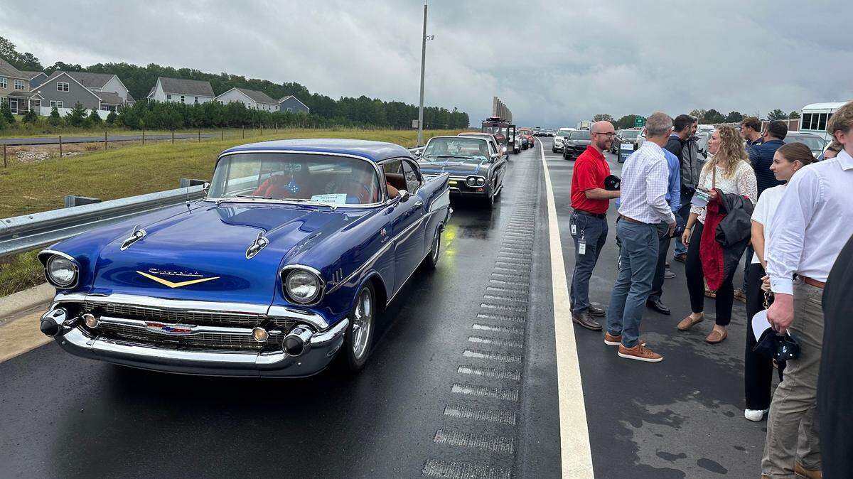 Members of the Southland Car Club of Smithfield make their way along the shoulder of N,C. 540 at the end of a ribbon-cutting ceremony on Tuesday. An 18-mile stretch of the six-lane toll road opens to the public Wednesday morning, Sept. 25, 2024.