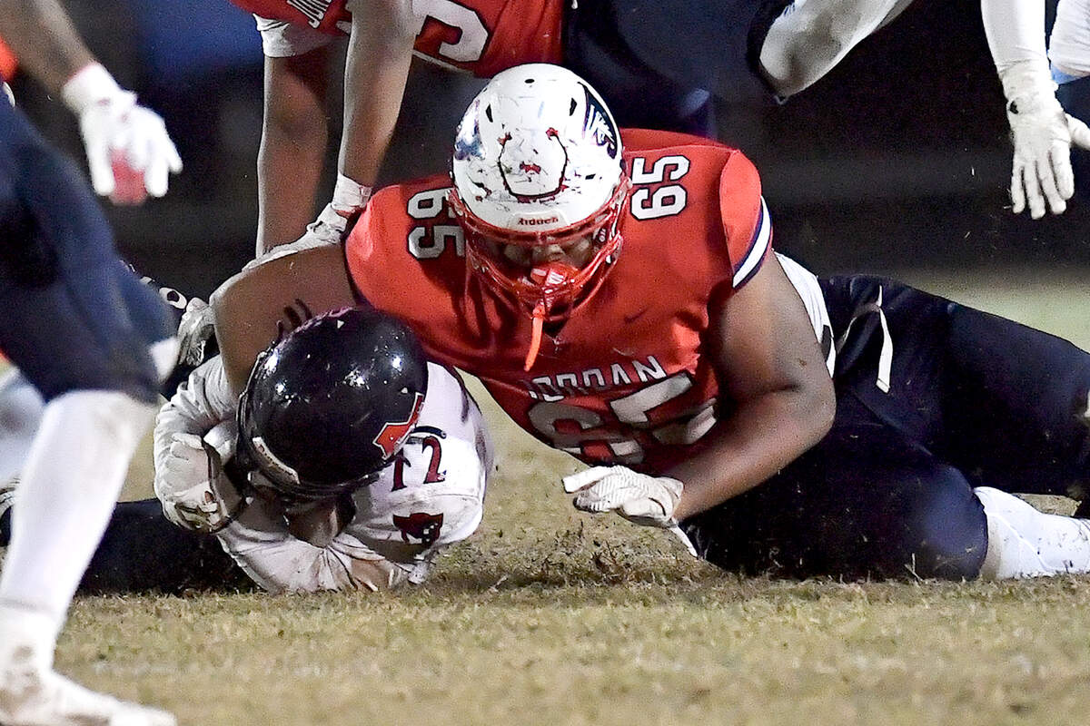 Jordan’s Noah Clark (65) tackles Apex Friendship’s Adam Schreiber (12) during the second half. The Apex Friendship Patriots and the Durham Jordan Falcons met in the second round of the NCHSAA 4A playoffs in Durham, N.C. on November 22, 2024.