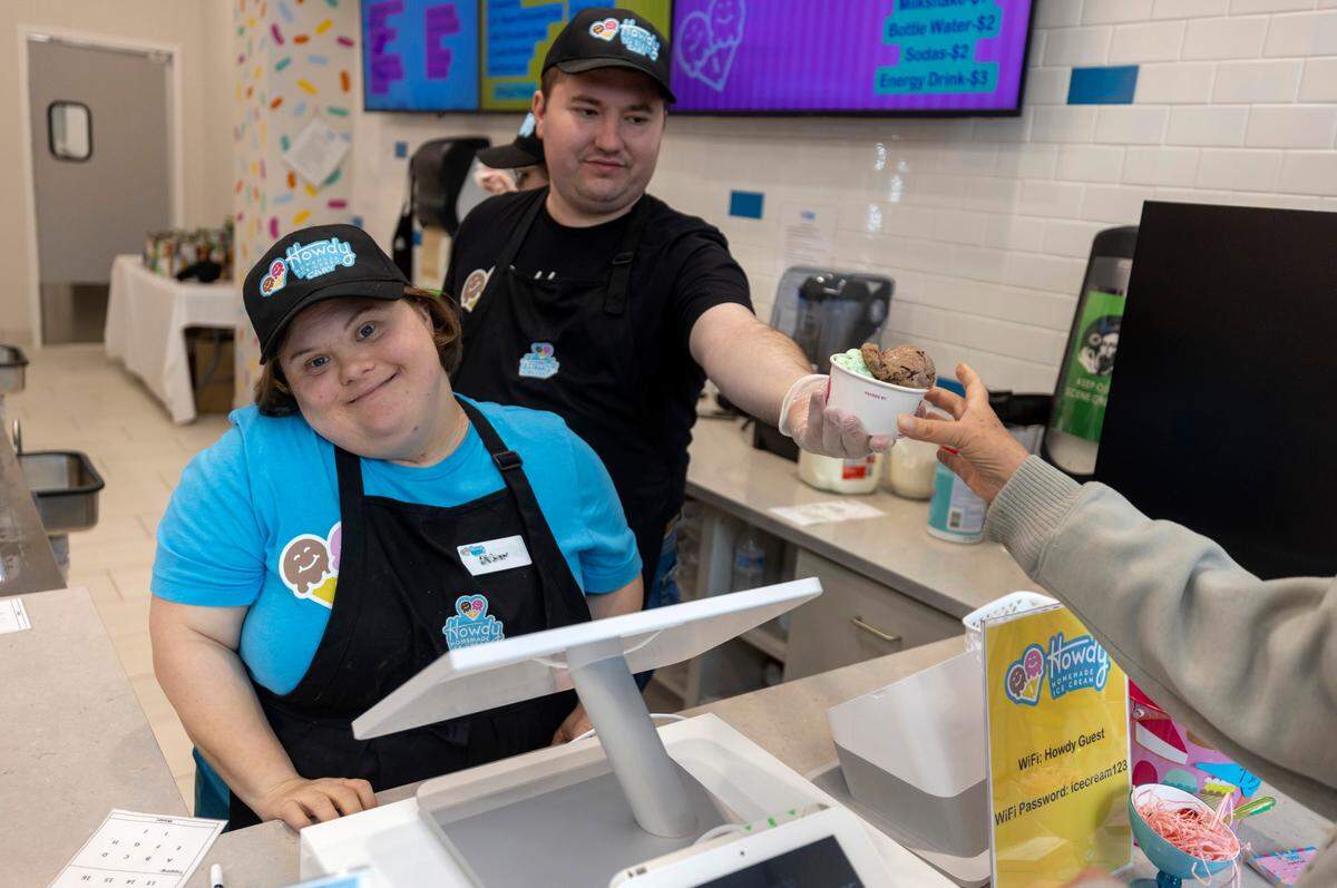 Daniel Marci, right, serves a customer while co-worker Abbey Goodwin works the cash register at Howdy Ice Cream on Thursday, March 2, 2023 in Cary, N.C. The new ice cream shop offers employment opportunities to individuals with intellectual developmental disabilities, where they can use their talents.