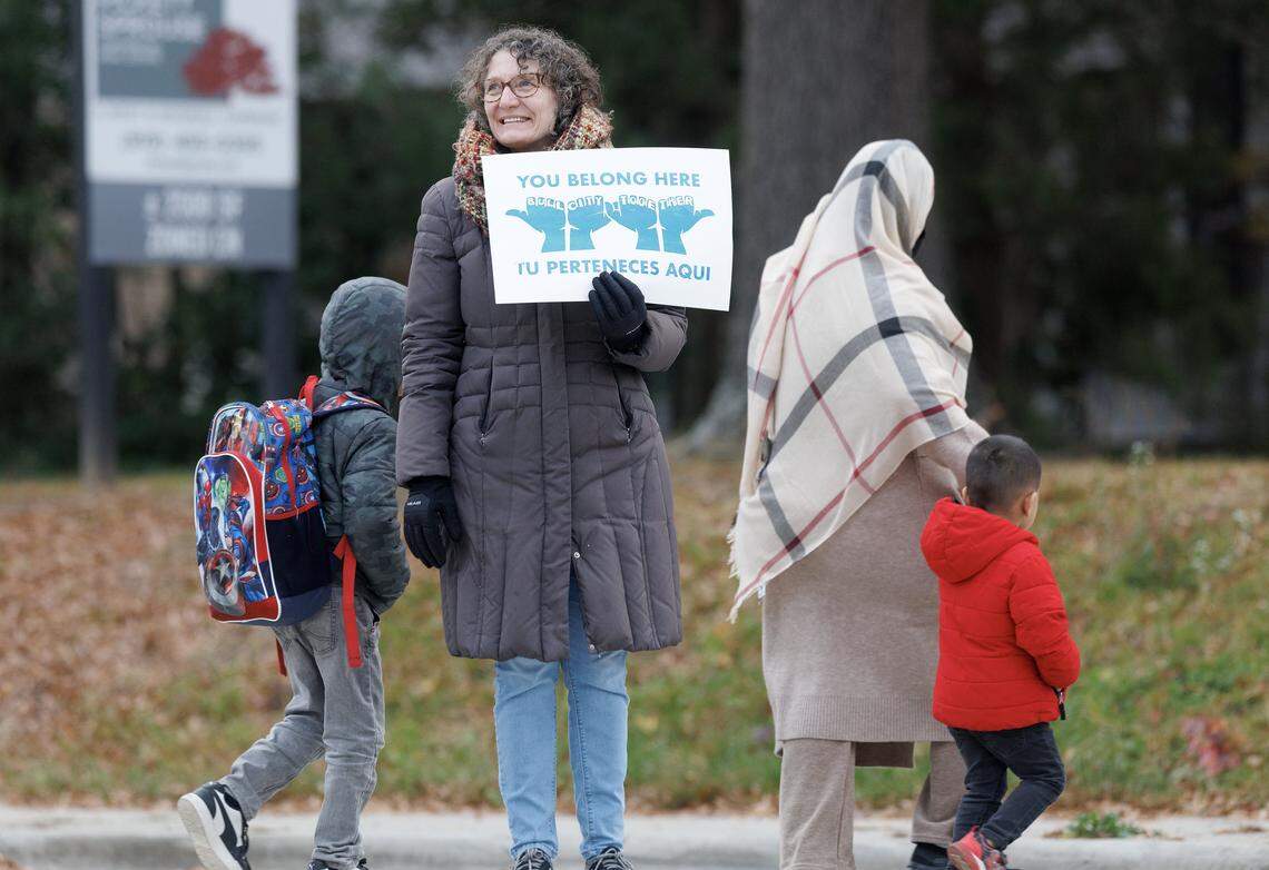 People walk by a member of a “School-Based Care and Protection Team,” an effort organized through Durham Public School Strong, Durham For All and other groups, on Thursday, Nov. 20, 2025, in Durham, N.C.