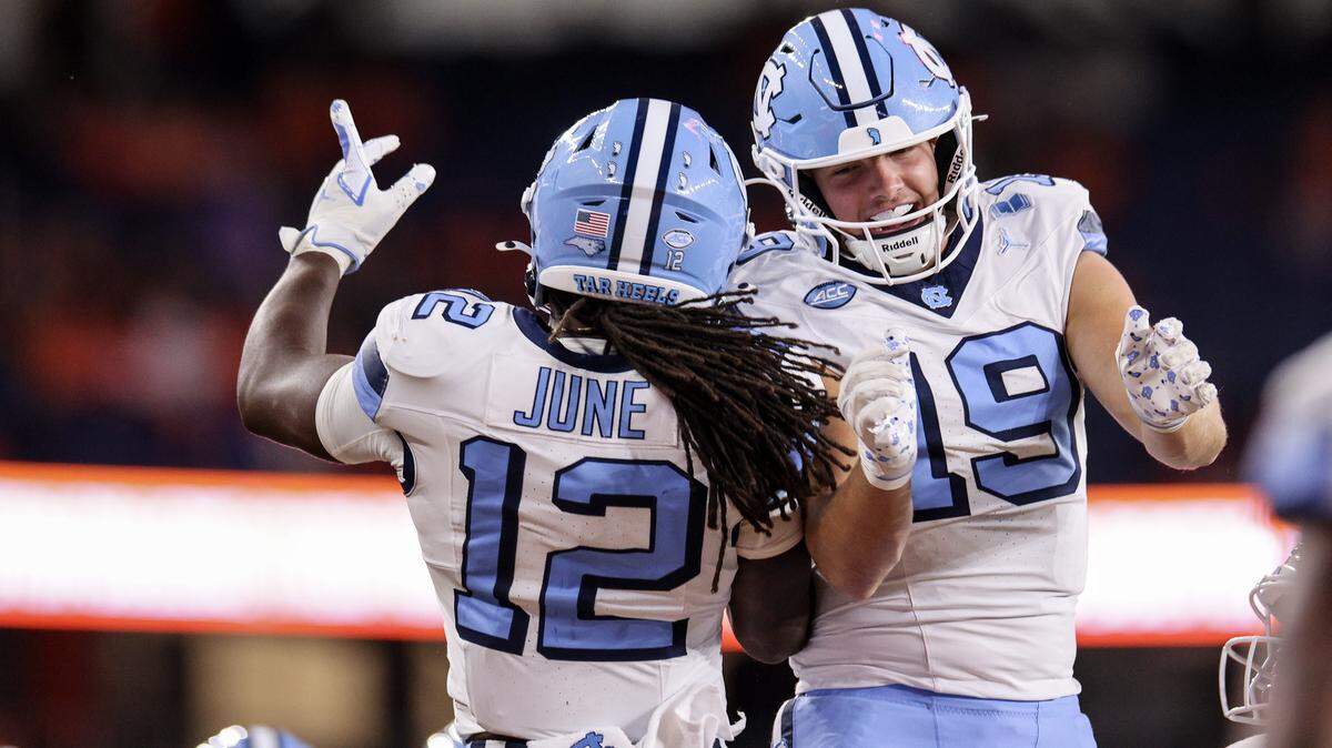 Demon June (12) and Jake Johnson of the North Carolina Tar Heels celebrate during the third quarter against the Syracuse Orange at JMA Wireless Dome on October 31, 2025 in Syracuse, New York.