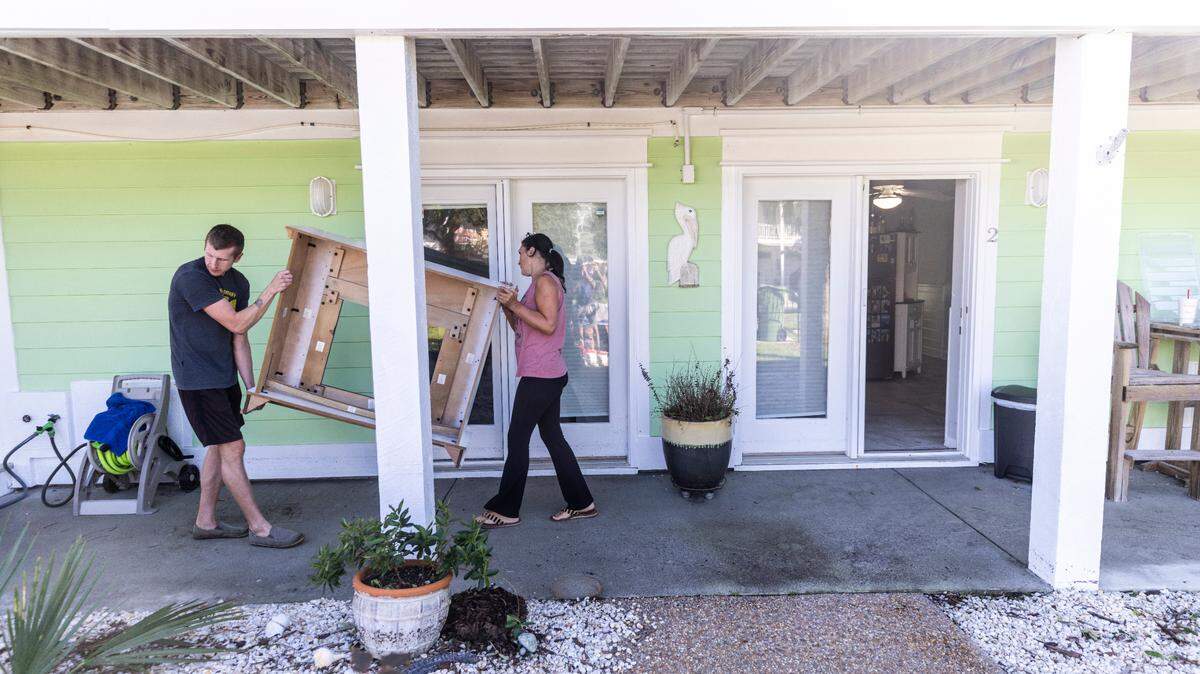 Chase Hobson helps his neighbor Shanda Rickert move furniture from Ricket’s flooded ground-level apartment in Kure Beach on Tuesday, Sept. 17, 2024 after an unnamed storm dropped as much as 18 inches of rain in southeastern North Carolina over a 72-hour period.