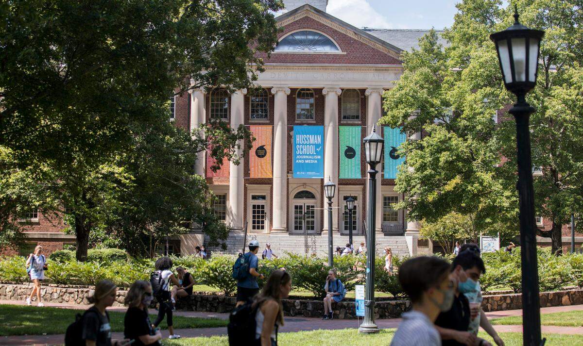 Students at UNC-Chapel Hill walk past Carroll Hall, which houses the Hussman School of Journalism and Media, in Chapel Hill, N.C. on Friday, Aug. 27, 2021.