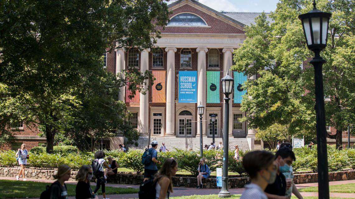 Students at UNC-Chapel Hill walk past Carroll Hall, which houses the Hussman School of Journalism and Media, in Chapel Hill, N.C. on Friday, Aug. 27, 2021.