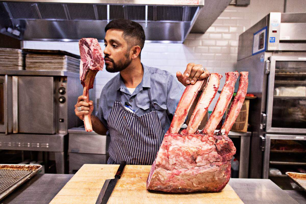 Vidrio chef Saif Rahman sniffs a tomahawk steak as he prepares for dinner service on Tuesday, April 26, 2022. Rahman fasts for 14 hours daily during the month of Ramadan and is not able to break his fast until sundown which occurs during dinner service.