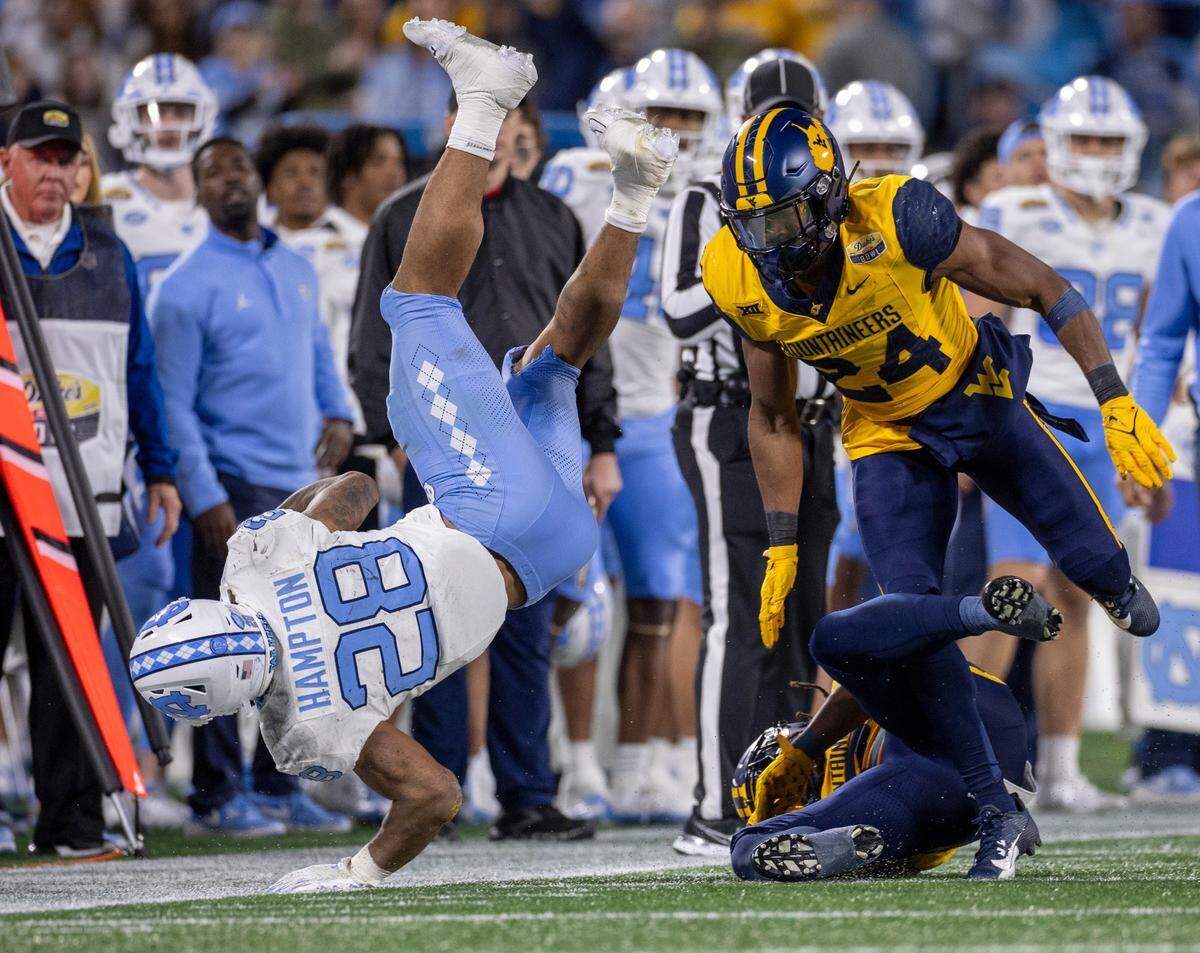 North Carolina’s Omarion Hampton (28) is stopped by West Virginia’s Marcis Floyd (24) after a six yard gain in the third quarter during the Duke’s Mayo Bowl on Wednesday, December 27, 2023 at Bank of American Stadium in Charlotte, N.C. Hampton was held to 74 yards rushing on 19 carries.