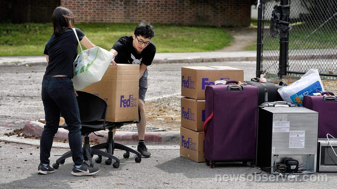 Duke freshmen Feng Cong from Singapore and Cassie Lu (left) from Thailand carry a box to a pile of their belongings as they move out of his dorm at Duke University. Sunday, March 15, 2020. Cong will be returning home to Singapore and Lu to Thailand since students are being asked to move out and complete classes online for the rest of the semester due to coronavirus.