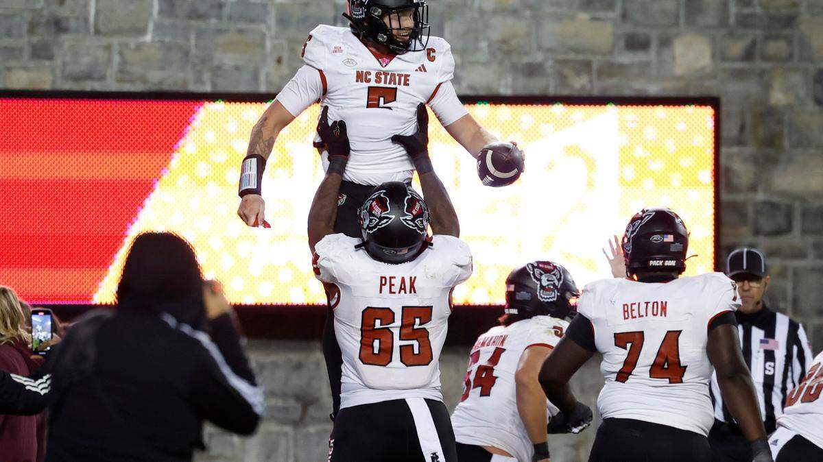 N.C. State offensive lineman Jacarrius Peak (65) lifts quarterback Brennan Armstrong (5) up after Armstrong scored on a one-yard touchdown run during the second half of N.C. State’s 35-28 victory over Virginia Tech at Lane Stadium in Blacksburg, VA, Saturday, Nov. 18, 2023.