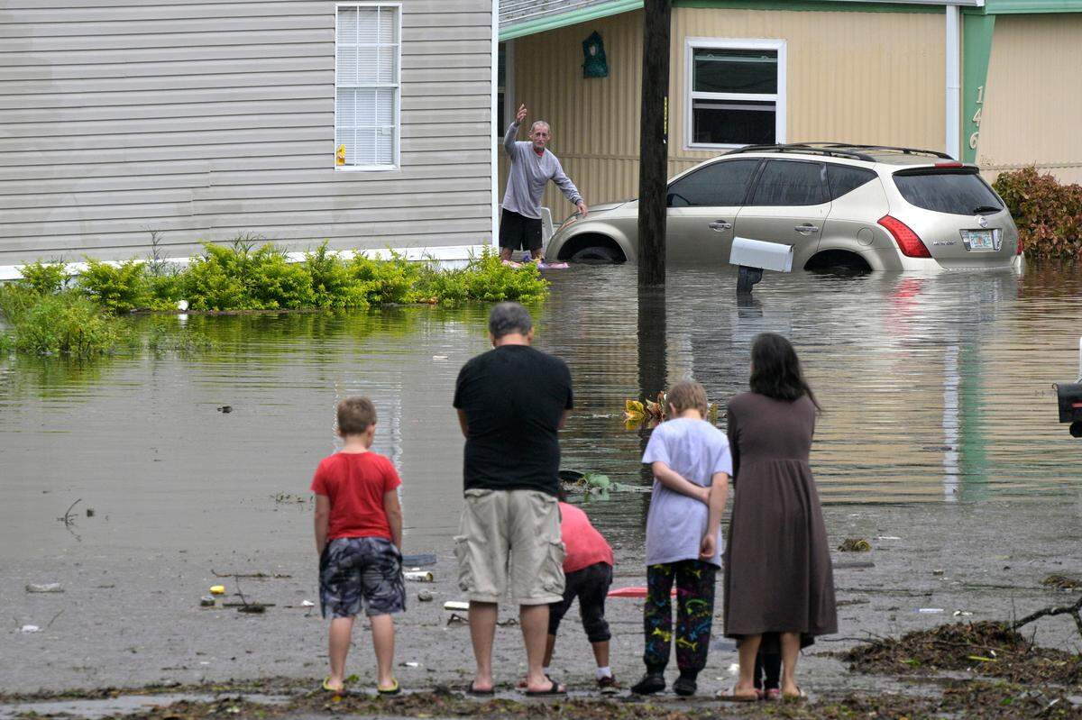 Residents check on one another in a flooded neighborhood in the aftermath of Hurricane Ian, Thursday, Sept. 29, 2022, in Orlando, Fla.
