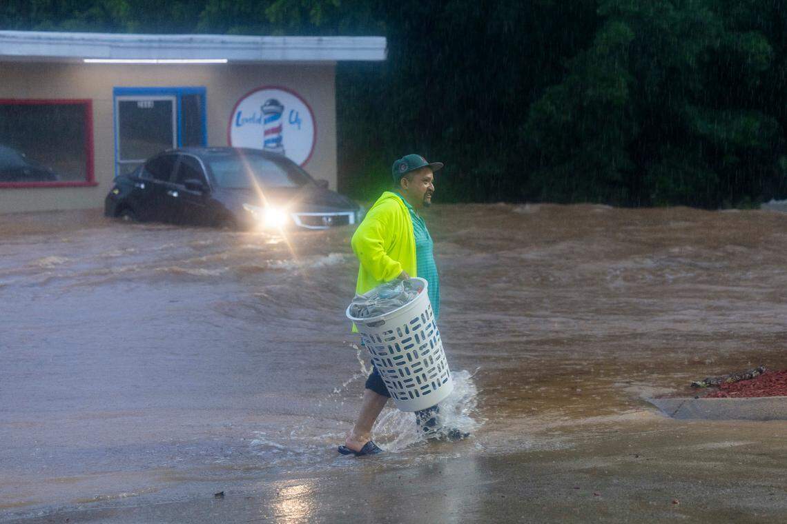 A laundromat patron wades through fast moving water that flooded Pittsboro Elementary School Road, engulfing the Laundry Land laundromat and the Leveled Up barbershop as Tropical Storm Chantal moved across the Triangle on Sunday, July 6, 2025.