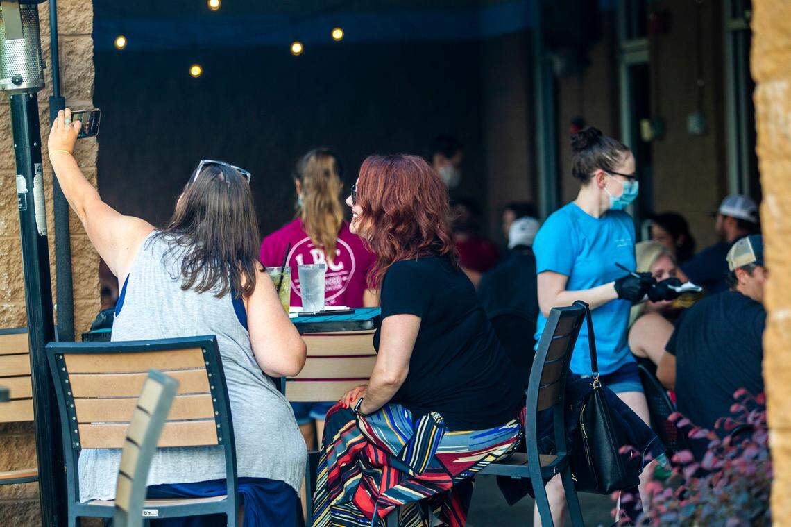 Michelle Priest, left, and Kim Sciandra take a selfie while waiting for food at Lynnwood Brewing Concerns Grove Barton Road location Friday, May 22, 2020. North Carolina entered Phase Two of its reopening plan Friday, allowing restaurants and personal care services to open at 50% capacity.