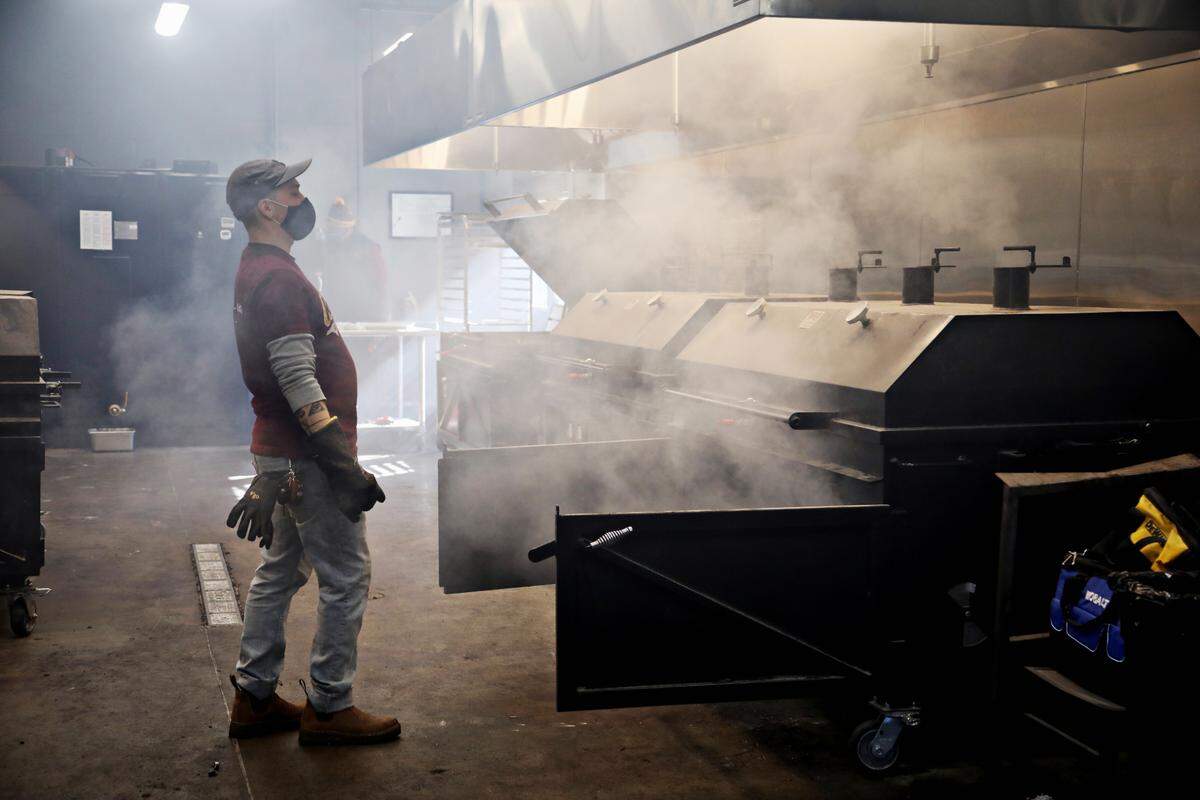 Sam Jones BBQ pit crew member Chris Wills steps back from the smoke as he works in the smokehouse in the new downtown Raleigh location on Wednesday morning, Feb. 3, 2021.