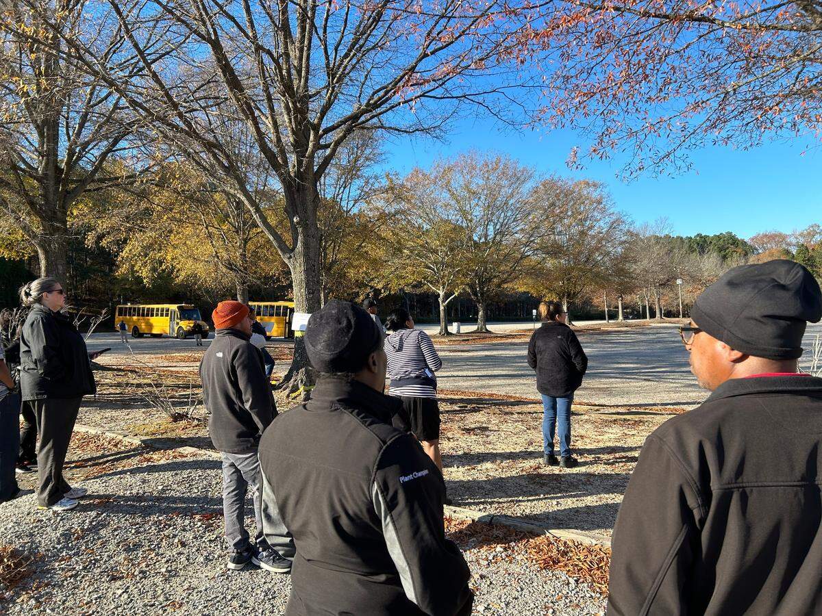 Parents wait in a parking lot at Walnut Creek Amphtheater on Nov. 27, 2023 to be reunited with their children after a student was fatally stabbed at Southeast Raleigh High School.