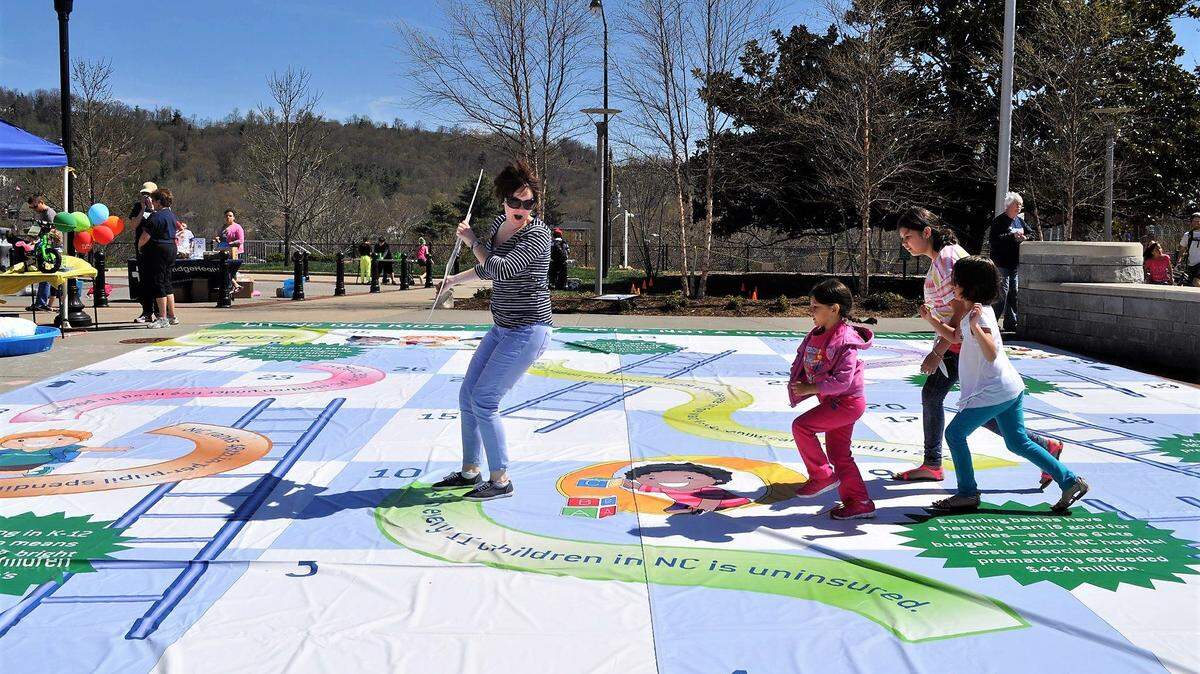 People play a poverty-based Chutes and Ladders game in this photo from a previous MomsRising North Carolina rally.