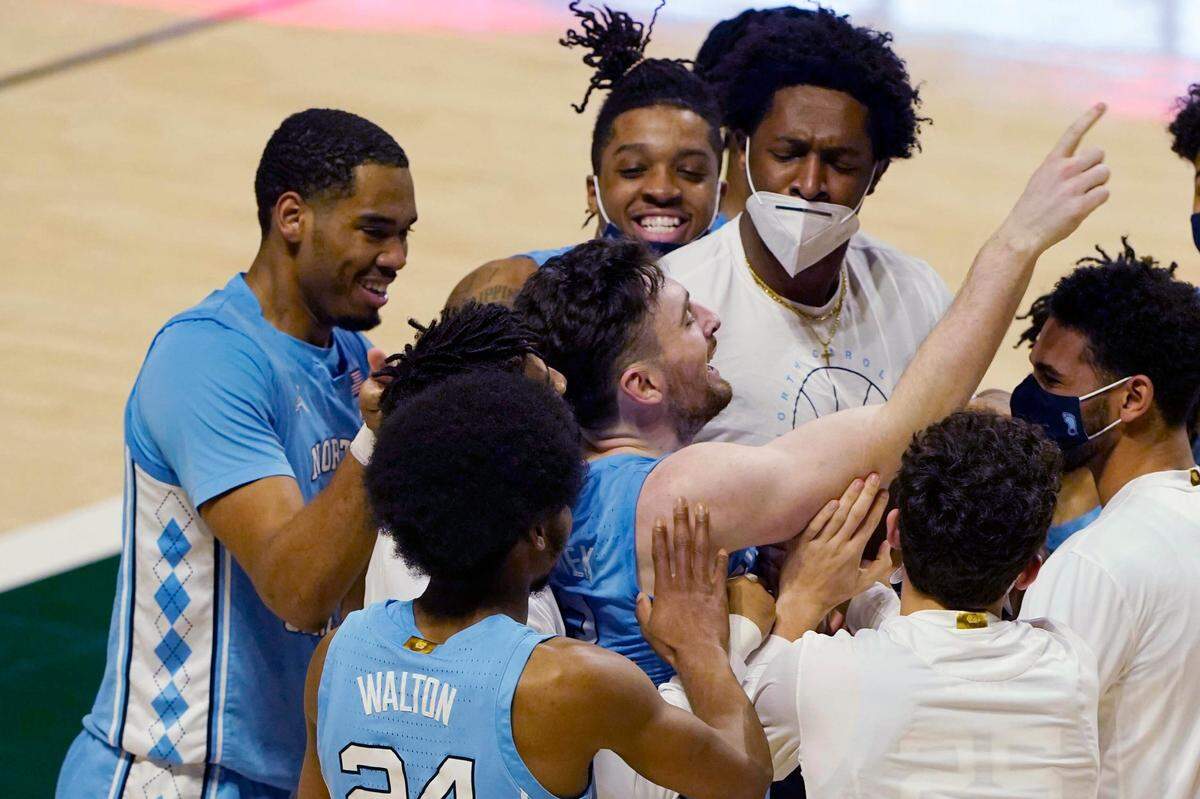 Teammates congratulate guard Andrew Platek (3), center, after he scored the winning basket during the second half of an NCAA college basketball game against Miami, Tuesday, Jan. 5, 2021, in Coral Gables, Fla. North Carolina defeated Miami 67-65.