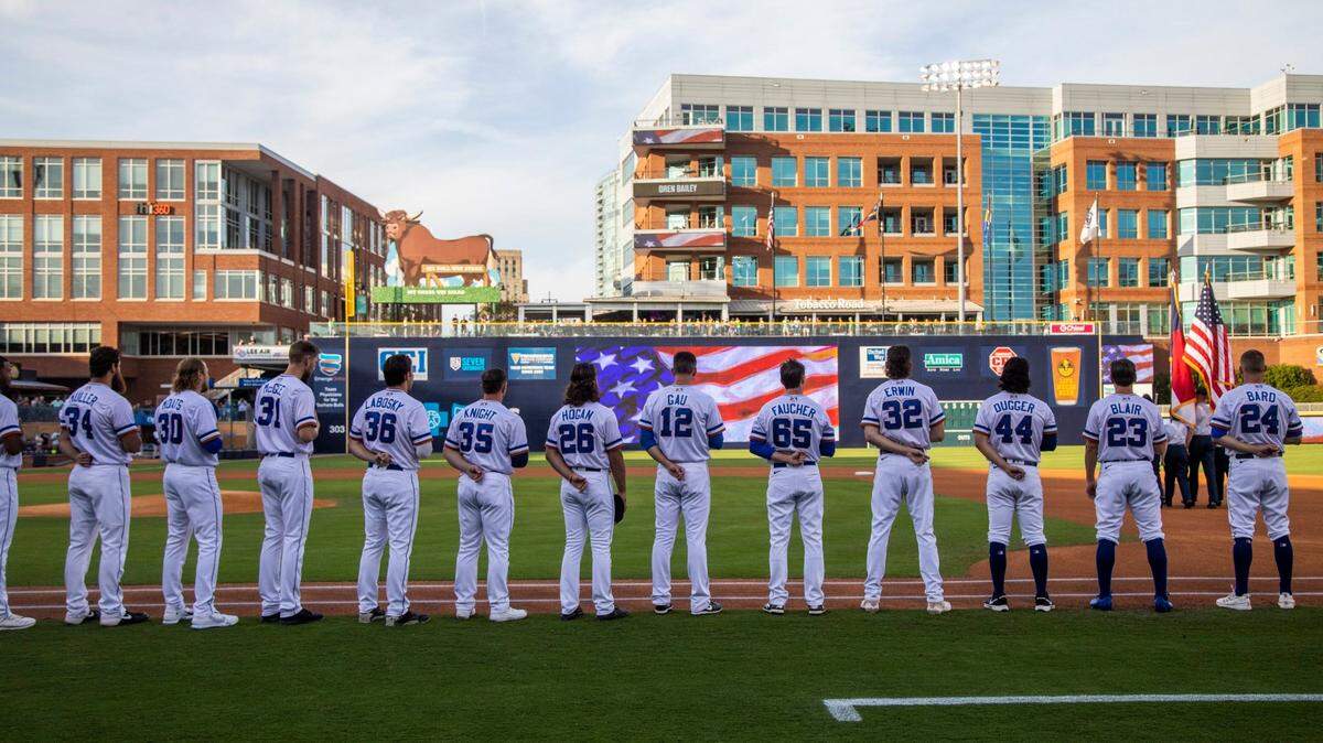 The Durham Bulls stand for the National Anthem prior to the Bulls season opener against the Jacksonville Jumbo Shrimp at the Durham Bulls Athletic Park, Tuesday, April 12, 2022.