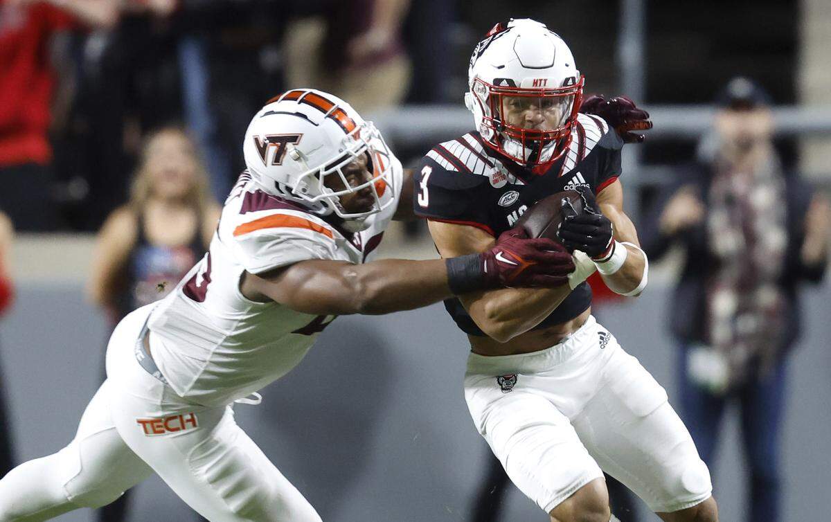 N.C. State running back Jordan Houston (3) tries to break free from Virginia Tech defensive lineman TyJuan Garbutt (45) during the first half of N.C. State’s game against Virginia Tech at Carter-Finley Stadium in Raleigh, N.C., Thursday, Oct. 27, 2022.