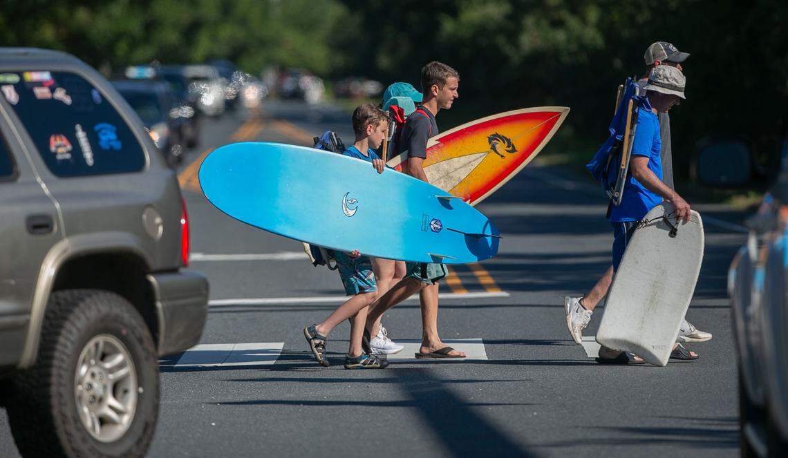 Beachgoers cross congested NC 12 on Sunday, June 27, 2021 in Southern Shores, N.C. Traffic is particularly heavy on Saturday and Sunday during the peak vacation season. At the intersection of NC 12 and Hillcrest Dr., traffic was crawling as vacationers use the only two lane road to Duck and Corolla on the northern outer banks.