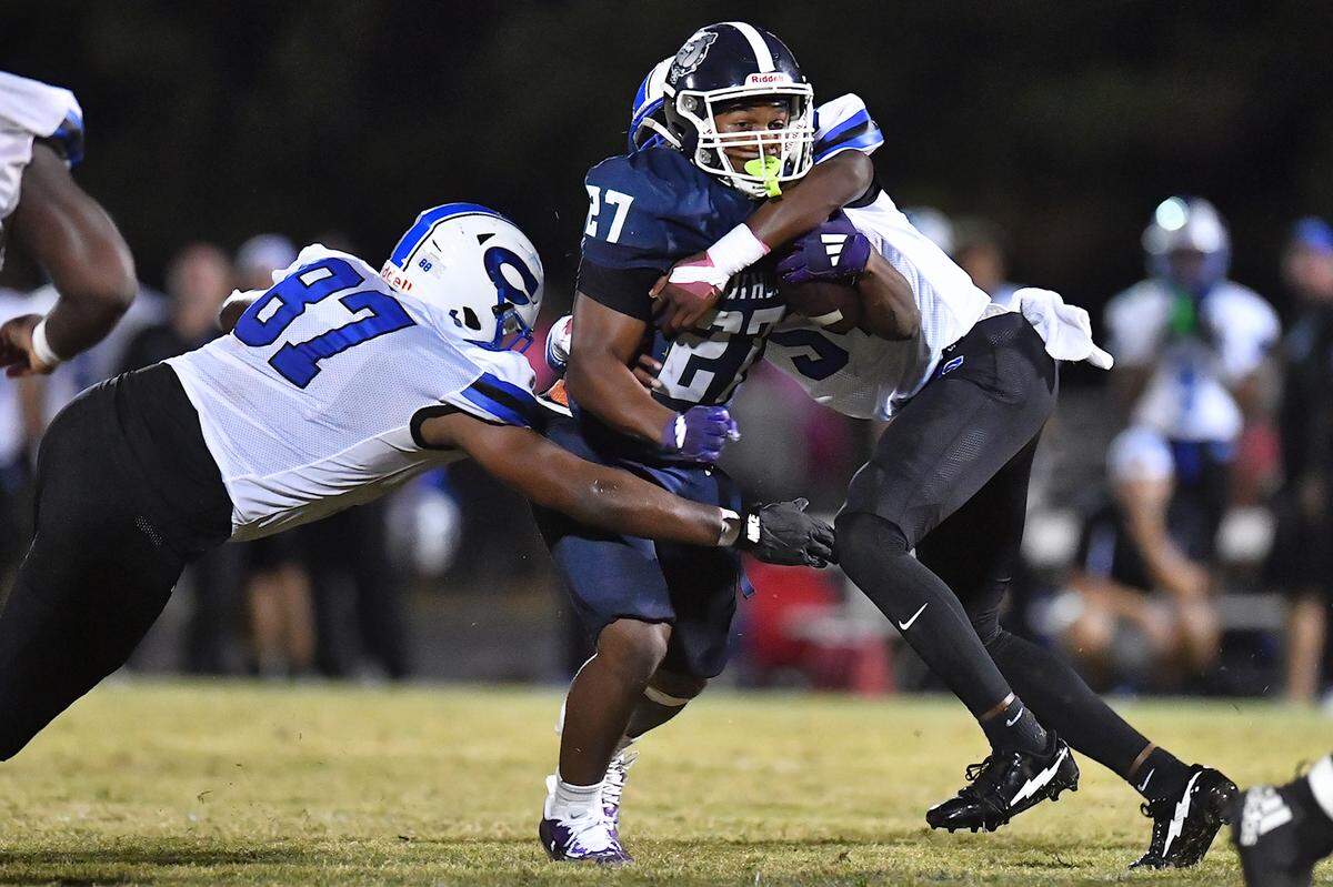 Southeast Raleigh running back James Adams IV (27) runs up the middle against Clayton's Zion Mosley (54) and Cedric Simmons (87) during the second half. The Southeast Raleigh Bulldogs and the Clayton Comets met in a non-conference football game in Raleigh, N.C. October 3, 2025