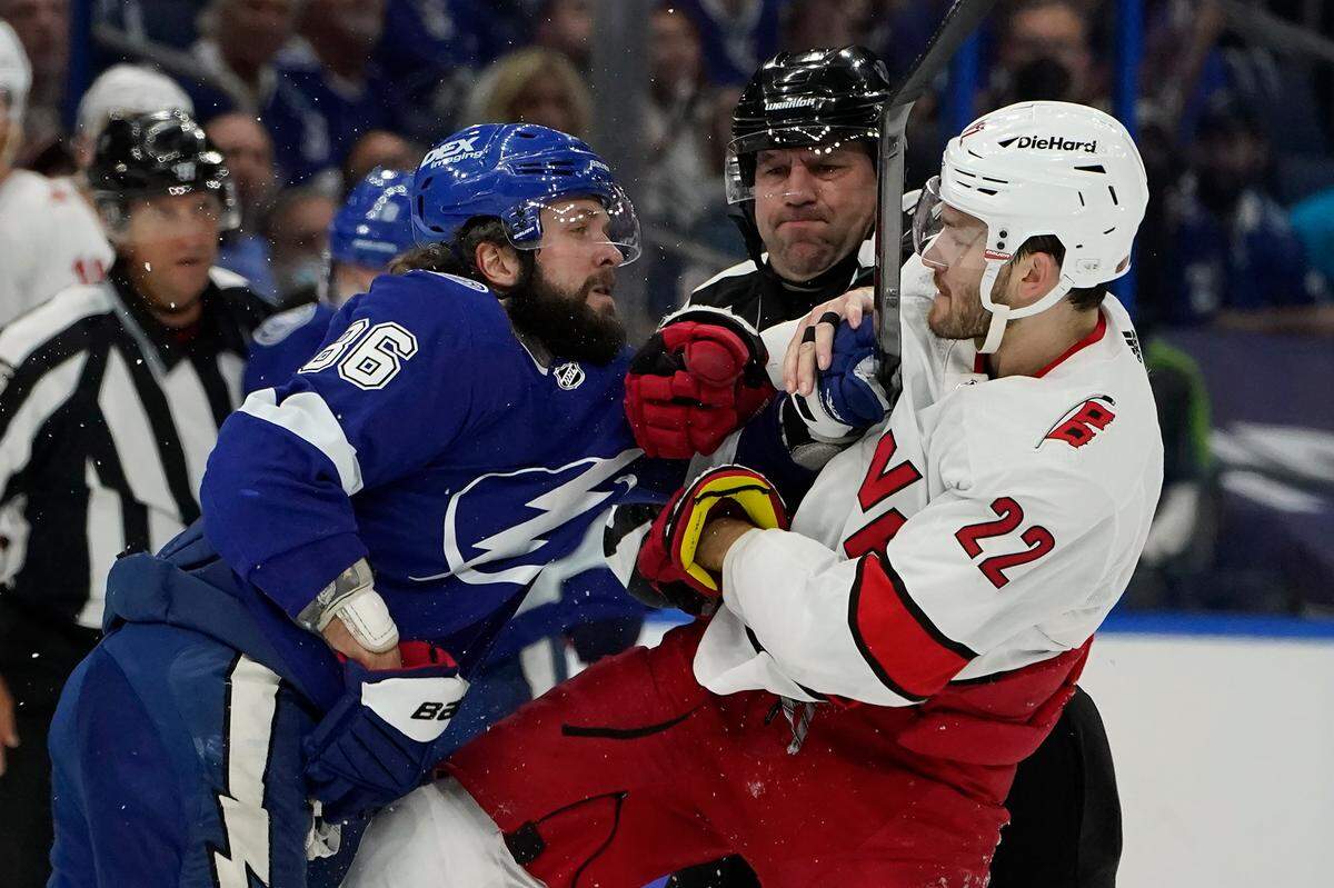 NHL linesman Lonnie Cameron (74) gets between Tampa Bay Lightning right wing Nikita Kucherov (86) and Carolina Hurricanes defenseman Brett Pesce (22) as they battle during the first period in Game 3 of an NHL hockey Stanley Cup second-round playoff series Thursday, June 3, 2021, in Tampa.