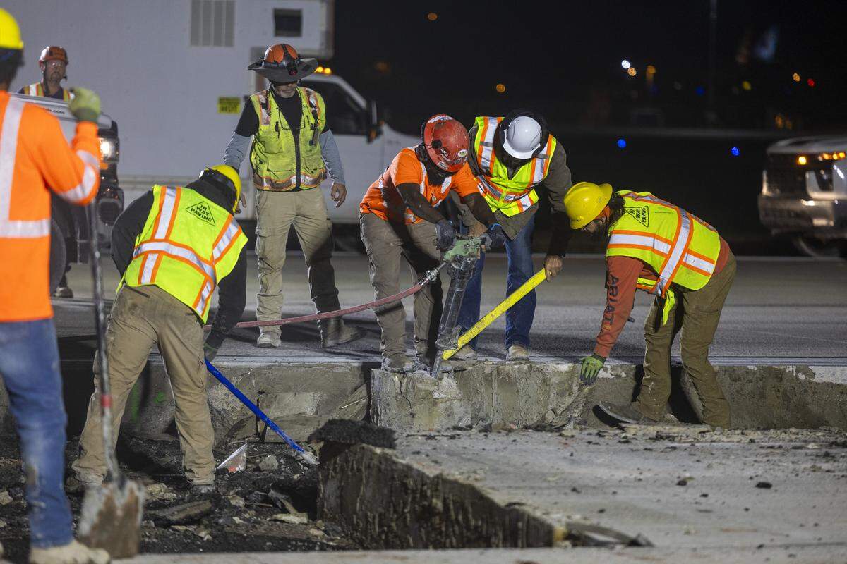 Workers with Hi-Way Paving remove asphalt from the hole they’re creating in runway 5L/23R. The worker with the jackhammer is chipping concrete from around a light can that holds one of the lights embedded in the runway.