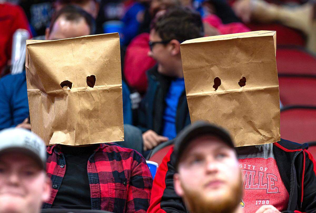 Two Louisville fans wore brown paper bags over their heads as the Louisville Cardinals and the Kentucky Wildcats faced off in their annual rivalry matchup at the KFC Yum Center in downtown Louisville on Thursday, Dec. 21, 2023.
