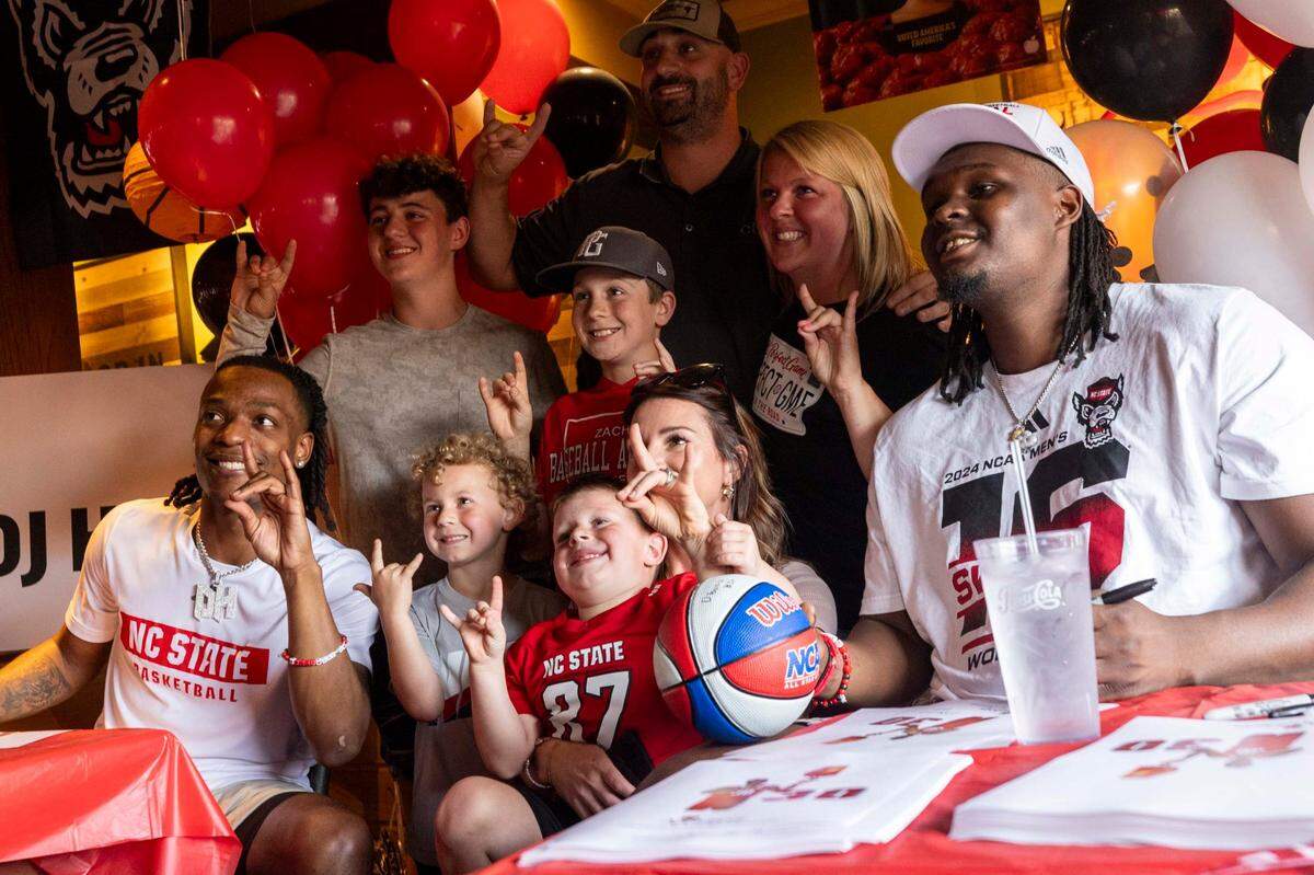 NC State’s DJ Horne, left, and DJ Burns Jr. pose for a photo with fans at the Triangle Town Center Applebee’s in Raleigh on Tuesday, April 2, 2024 ahead of the Wolfpack’s Final Four game on Saturday.