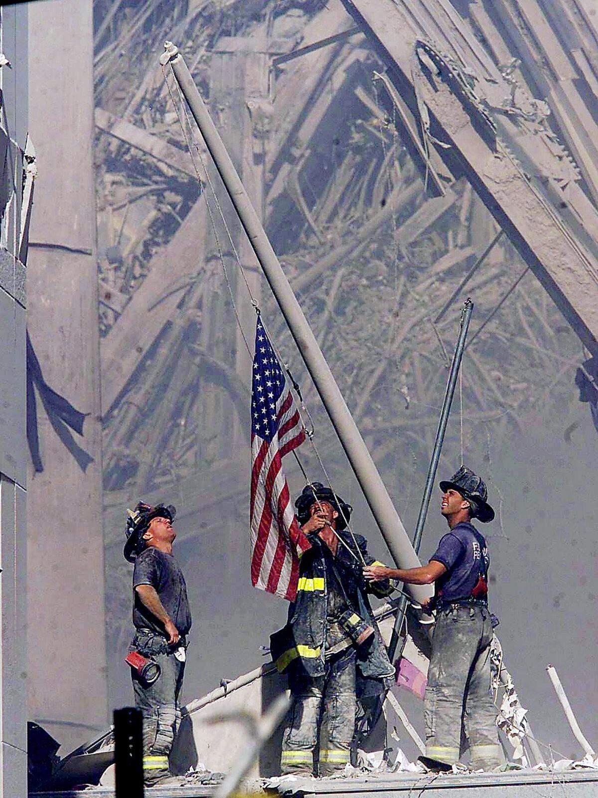 Firefighters raise a flag late in the afternoon on Tuesday, Sept. 11, 2001, in the wreckage of the World Trade Center towers in New York.