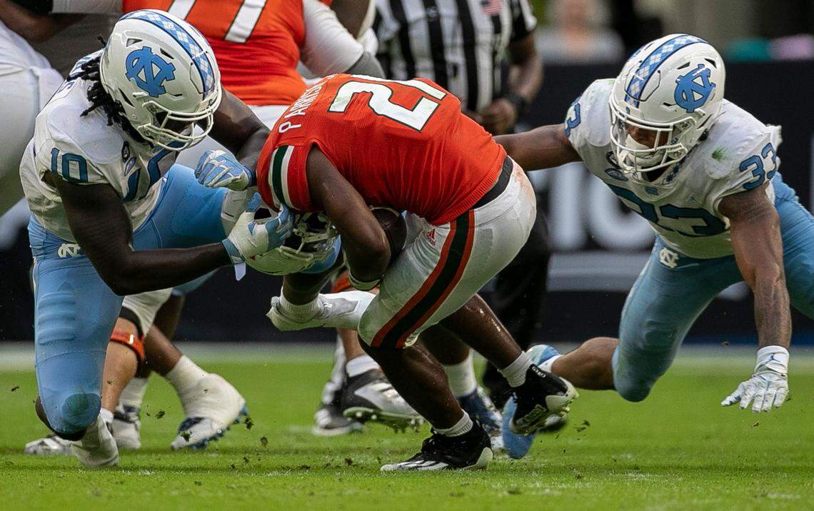 Miami’s Henry Parrish Jr (21) is stopped for a loss by North Carolina’s Desmond Evans (10) and Cedric Gray (33) in the third quarter on Saturday, October 8, 2022 at Hard Rock Stadium in Miami Gardens, Florida.