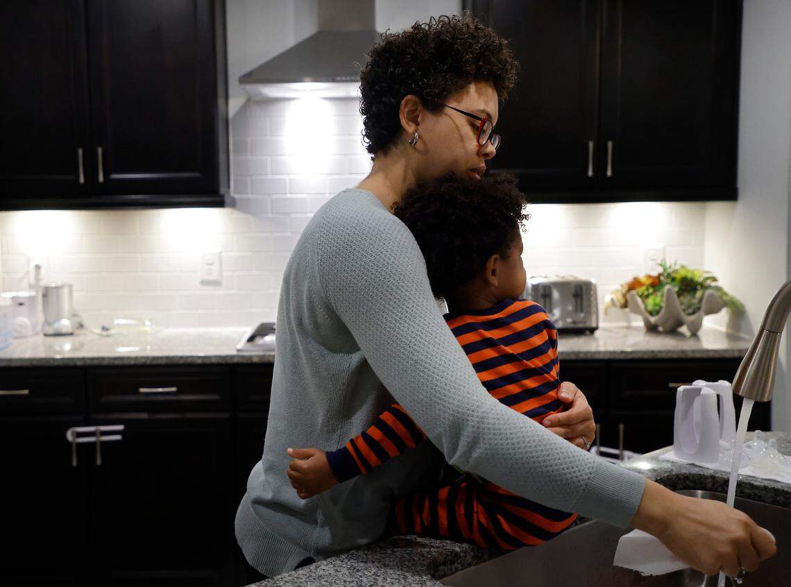 Ashly Gaskin-Wasson hugs her one-year-old child, Channing, as she stands in the kitchen of their Durham, N.C. home on Wednesday, Dec. 7, 2022. Gaskin-Wasson, a psychologist, worked from home to be able to care for her two young children, both of whom are battling symptoms of upper respiratory illness.