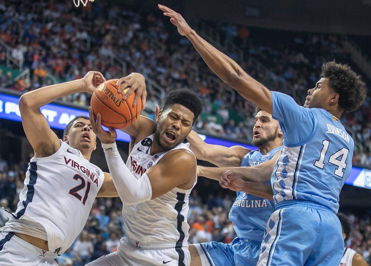 Virginia’s Jayden Gardner (1) secures a defensive rebound over North Carolina’s Pete Nance (32) and Puff Johnson (14) late in the second half during the third round of the ACC Tournament on Thursday, March 9, 2023 at the Greensboro Coliseum in Greensboro, N.C.
