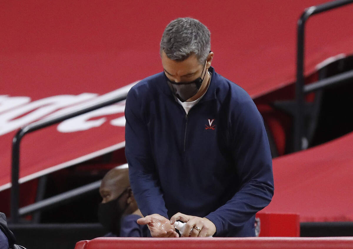 Virginia head coach Tony Bennett squirts sanitizer on his hands during the second half of Virginia’s 64-57 victory over N.C. State at PNC Arena in Raleigh, N.C., Wednesday, February 3, 2021.