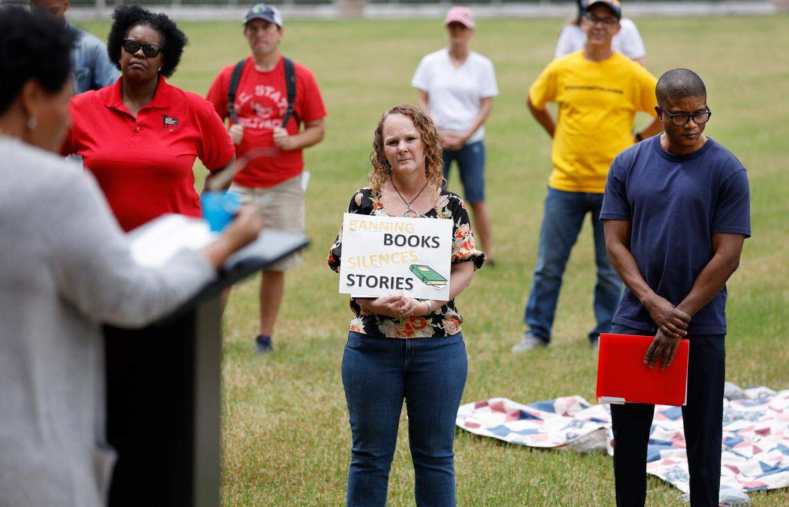 Becky Showalter, center, and William Johnson, right, listen as Janice Robinson reads from The Hate U Give by Angie Thomas during a ‘Celebration of Banned Books’ at Halifax Mall in downtown Raleigh, N.C., Saturday, May 7, 2022.