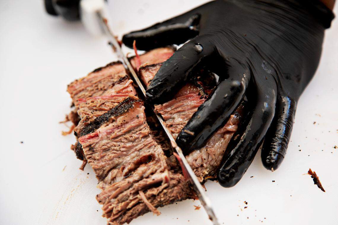 Longleaf Swine’s pit master Marc Russell slices brisket at the Bubbles & Brisket event at Smoky Hollow in Raleigh on Saturday, June 4, 2022.