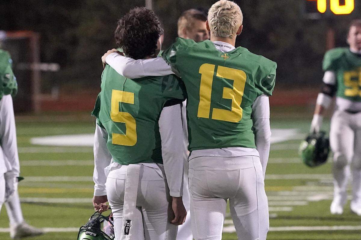 Cardinal Gibbons' Hudson VanDyke (5) is consoled by Connor McGeehan (13) after their team's loss to Clayton in the NCHSAA 7A East Regional Final. The Clayton Comets and the Cardinal Gibbons Crusaders met in the East Regional Final of the NCHSAA 7A Football Championship in Clayton, N.C. on December 4, 2025.