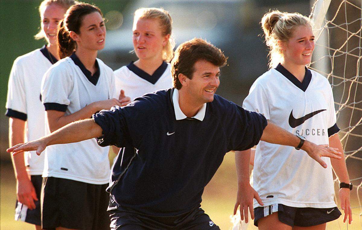 UNC women’s soccer coach Anson Dorrance positions his body to demonstrates defensive positioning during a strenuous practice at Finely Field in 1998. One of Dorrance’s favorite expressions during both practice and games is, “Do something dynamic!”. From left: Helen Lawler, Raven McDonald, Meredith Florance and Anne Remy.