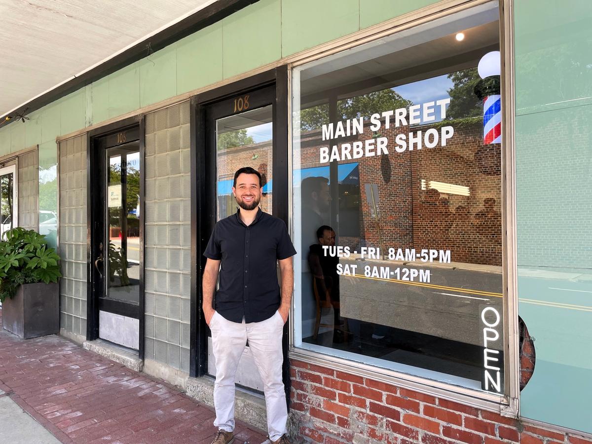Jeremy Anderson, 38, takes a break from the hustle of haircuts and hot-lather shaves outside Main Street Barber Shop in downtown Carrboro on Wednesday, May 7, 2025. The new shop replaces Friendly Barber Shop, which closed at the end of April after 64 years.