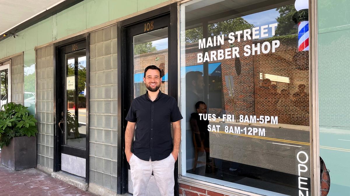 Jeremy Anderson, 38, takes a break from the hustle of haircuts and hot-lather shaves outside Main Street Barber Shop in downtown Carrboro on Wednesday, May 7, 2025. The new shop replaces Friendly Barber Shop, which closed at the end of April after 64 years.