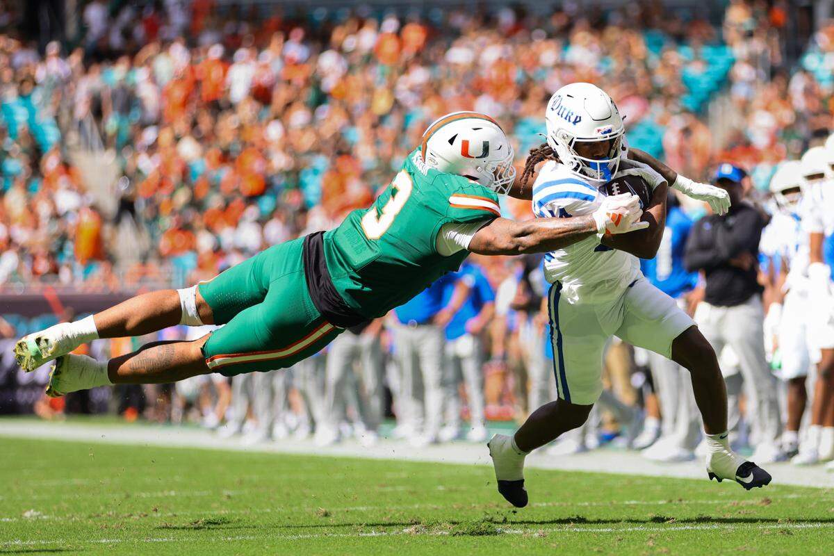 Nov 2, 2024; Miami Gardens, Florida, USA; Duke Blue Devils wide receiver Que’Sean Brown (14) runs with the football past Miami Hurricanes defensive lineman Akheem Mesidor (3) during the second quarter at Hard Rock Stadium. Mandatory Credit: Sam Navarro-Imagn Images