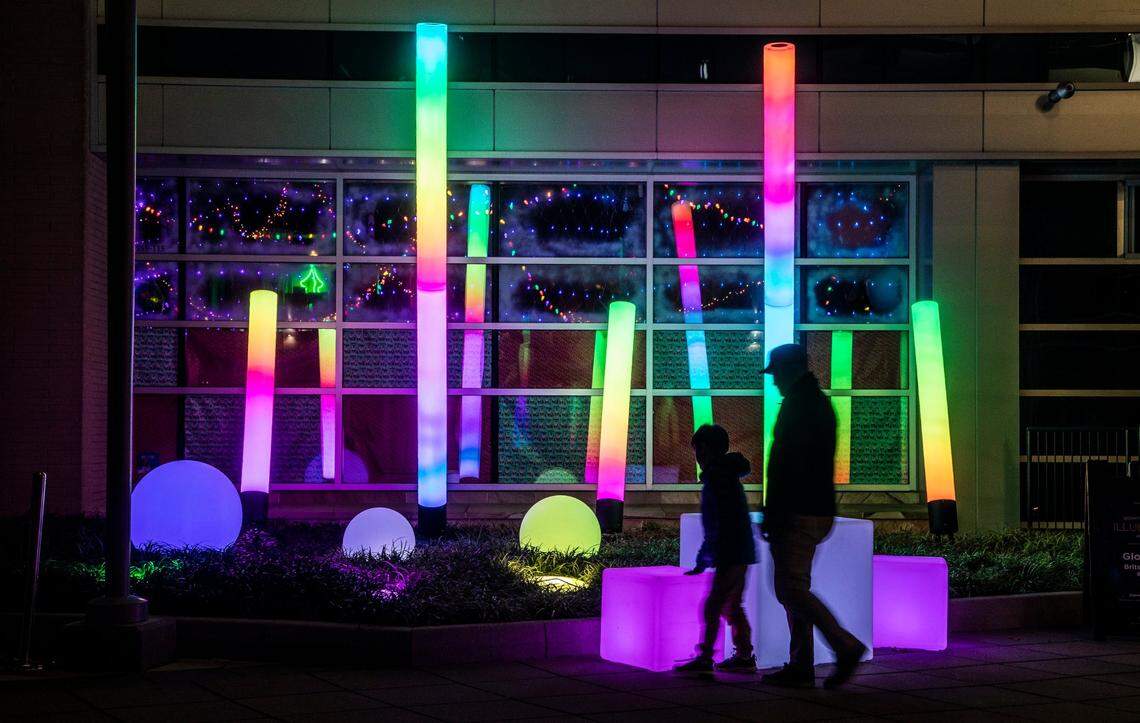 Pedistrians check out the “Glow Zone”in City Plaza in downtown Raleigh Friday, Dec. 2, 2022. The large-scale, interactive light-based art piece is one of 18 installations around downtown Raleigh and the Glenwood South district that make up the Illuminate Art Walk presented by Wake Tech.