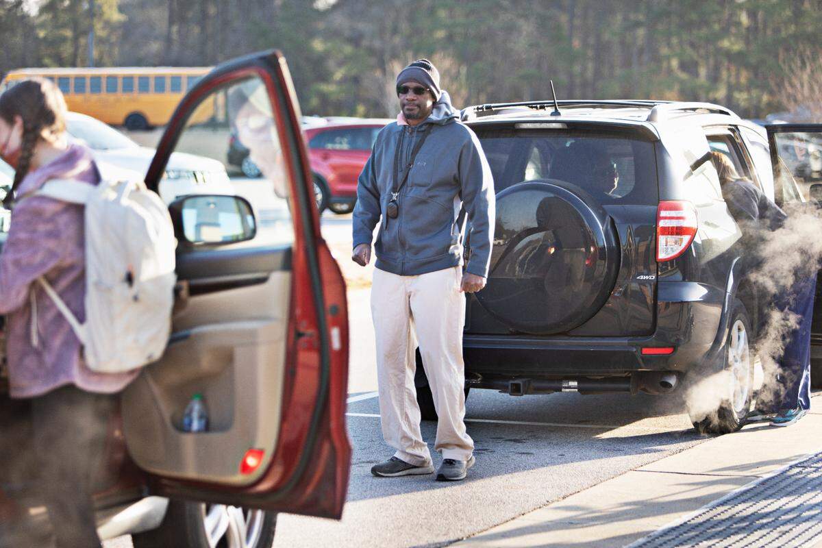 Swift Creek Middle School teacher Jeffery Waters directs traffic during Monday morning’s drop-off on Feb. 21, 2022, in Clayton. This marks the first day that masks may be optional in Johnston County schools. Waters, a STEM teacher at Swift Creek, said his students are divided on the mask debate.