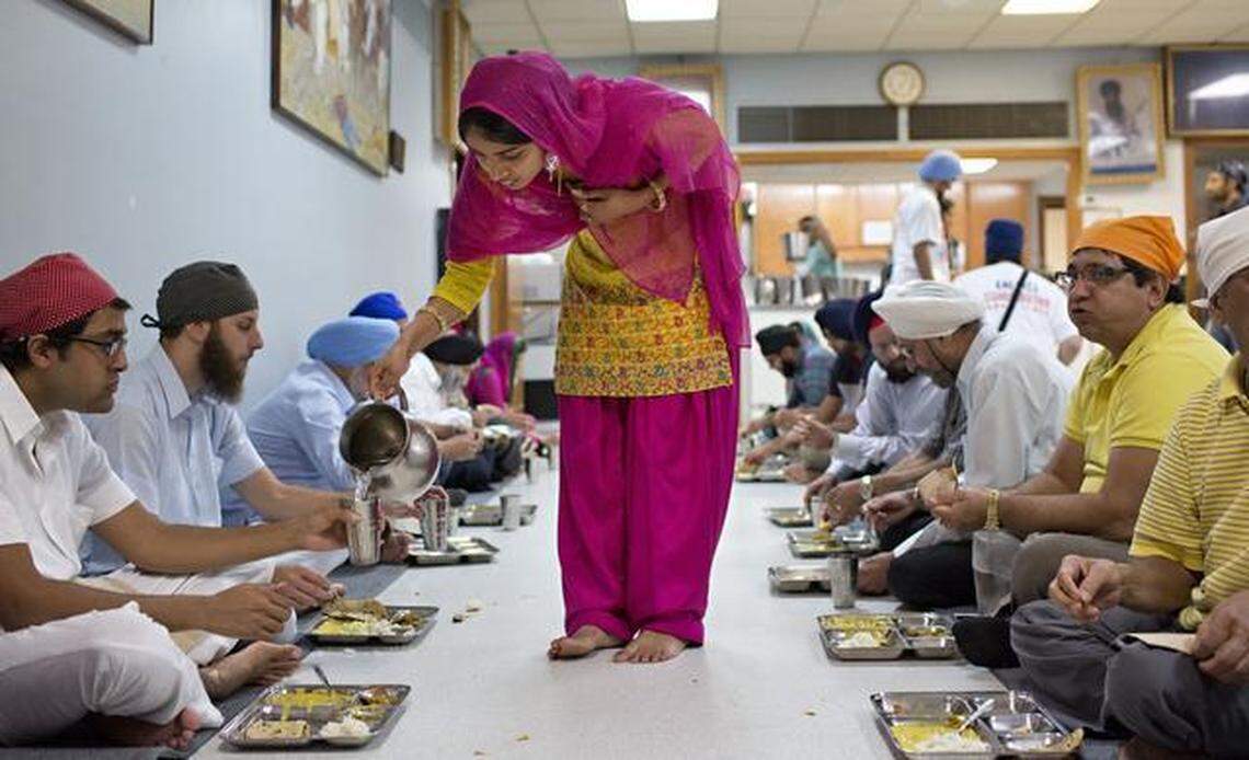 Kaml Kaur, center, serves water during “langar” on Sunday. Sikh Gurdwara members collected cash and food donations for the Food Bank of Central and Eastern North Carolina.