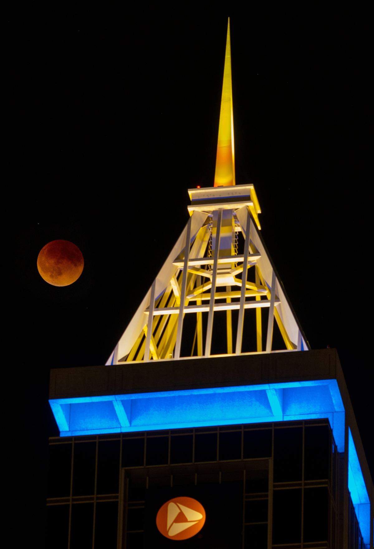 The moon rises above the PNC Tower in downtown Raleigh, N.C. at 12:36 AM Sunday during the total eclipse, also known as the blood moon. The Earth moved into position between the sun and the full moon casting a giant shadow across the moon’s surface, giving the it a striking reddish color.