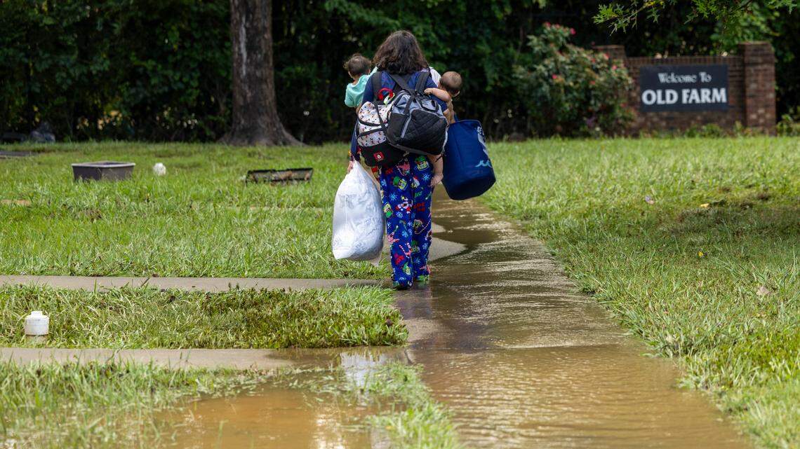 Residents walk with their belongings at Rippling Streams Townhomes in the Old Farm neighborhood along the Eno River in Durham on Monday morning, July 7, 2025, after flash flooding caused by Tropical Storm Chantal.