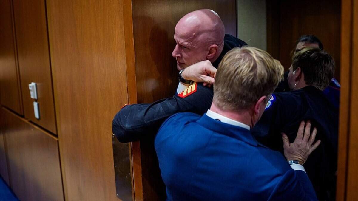 WASHINGTON, DC - MARCH 4: Brian McGinnis, a protester dressed in a military uniform, gets stuck in a door, injuring his arm, as Sen. Tim Sheehy (R-MT) (R) and U.S. Capitol Police officers attempt to remove him from a Senate Armed Services Subcommittee hearing on Capitol Hill on March 4, 2026 in Washington, DC. The protester has been identified as Brian McGinnis from North Carolina. The Subcommittee on Readiness and Management Support is holding a hearing to examine the current readiness of the Joint Force. (Photo by Andrew Harnik/Getty Images)