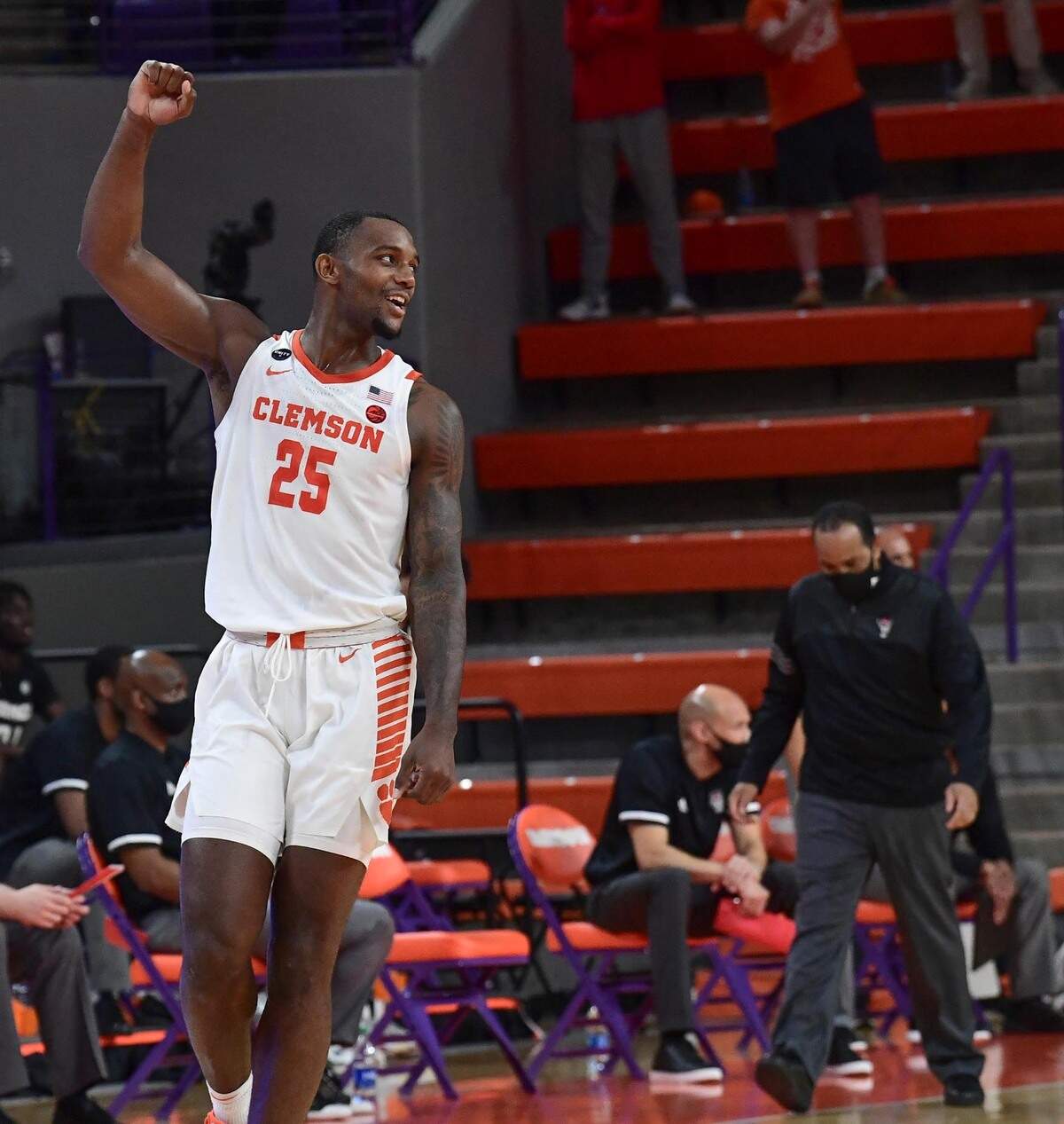 Clemson senior forward Aamir Simms(25) raises his fist near NC State head coasch Kevin Keatts, right, after the Tigers beat N.C. State 74-70 in overtime Jan 5, 2021.